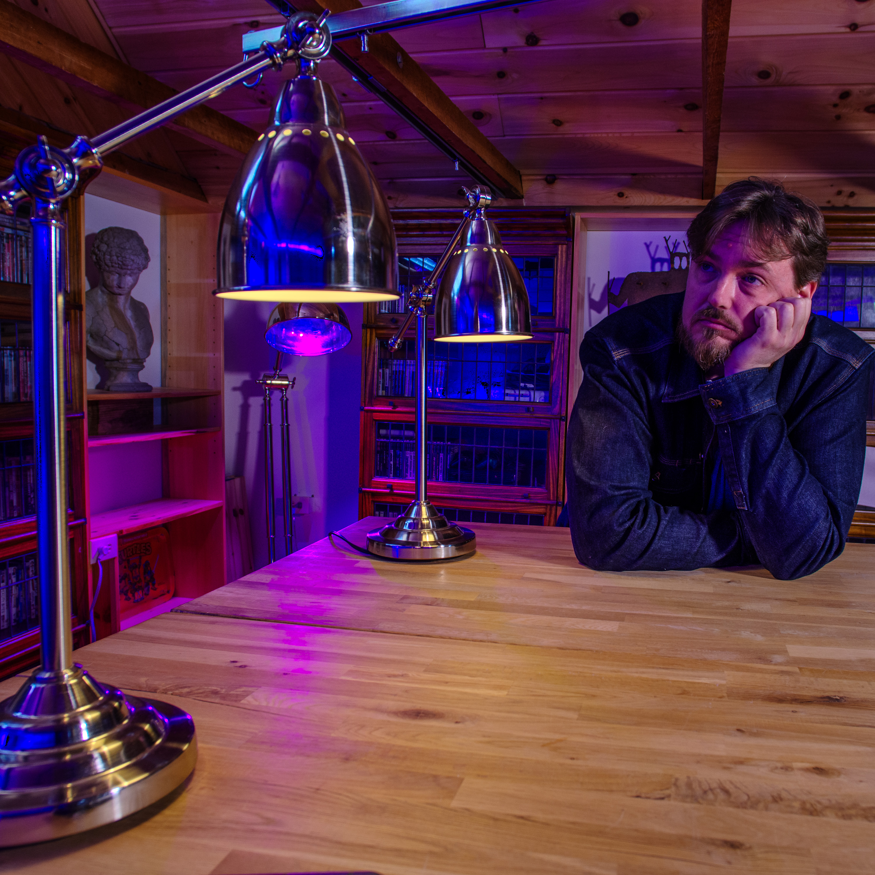 A contemplative SW Hammond sitting in his office. Dynamic purple and blue lighting fills the background.